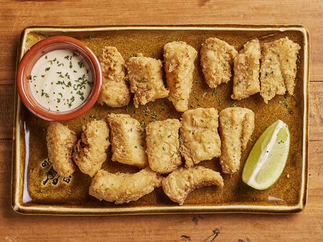 Delicious crispy fried fish tapas served with sauce and lemon at El Pimiento Restaurant, Miami Lakes